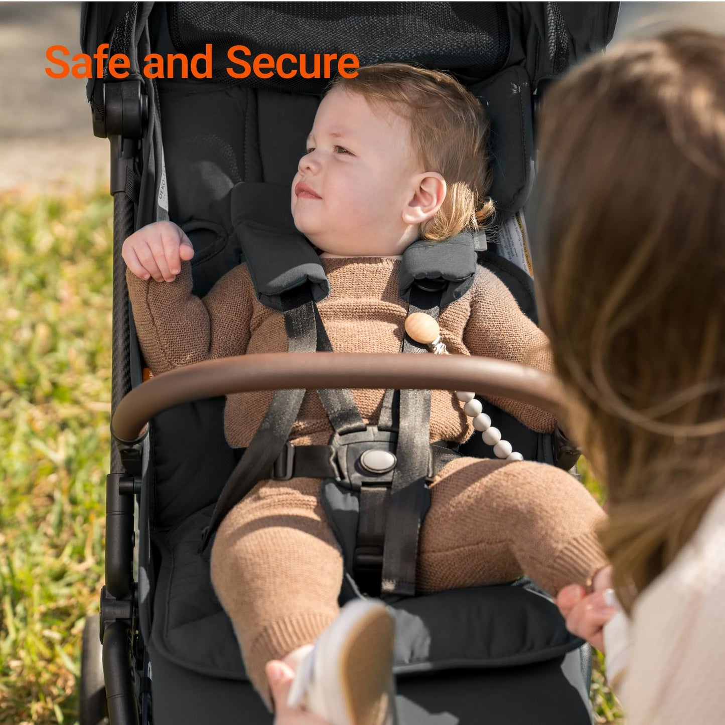 Child in a stroller with a woman outdoors, text 'Safe and Secure' above.