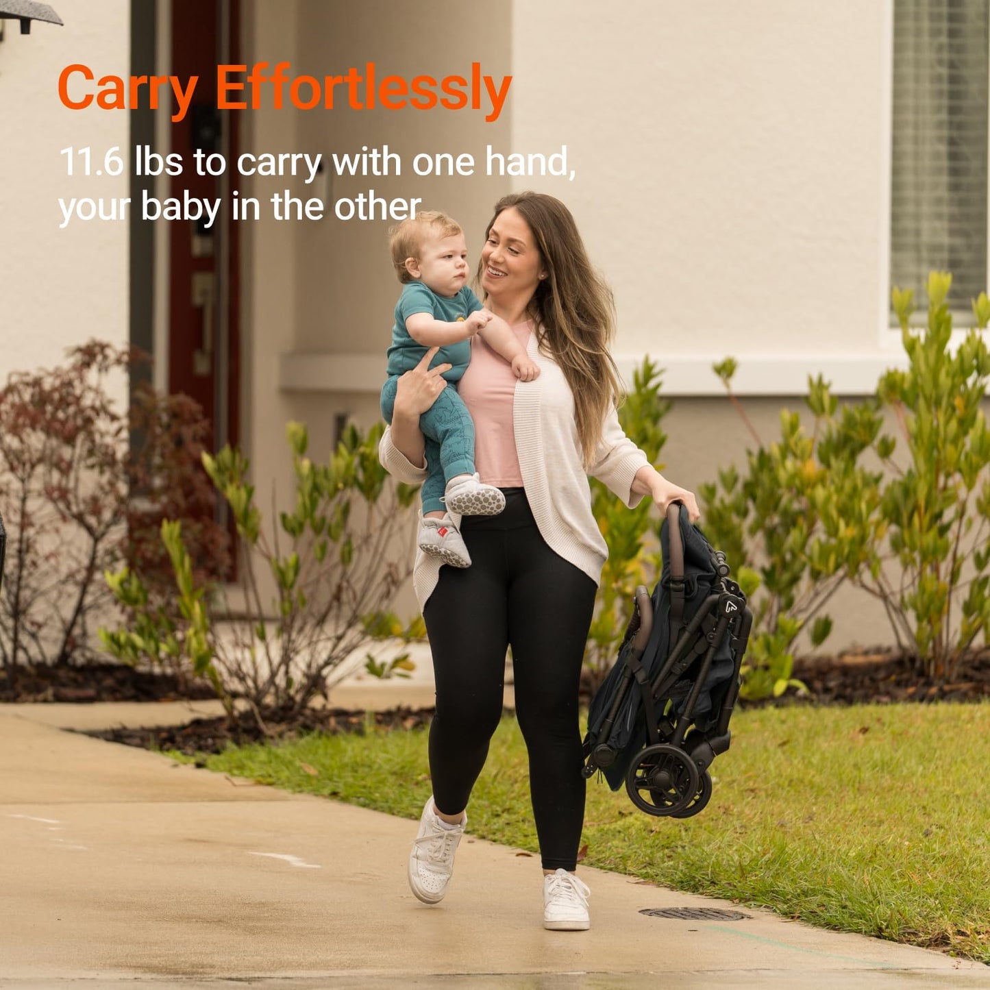 Woman carrying a baby and a stroller with text about weight capacity outdoors.