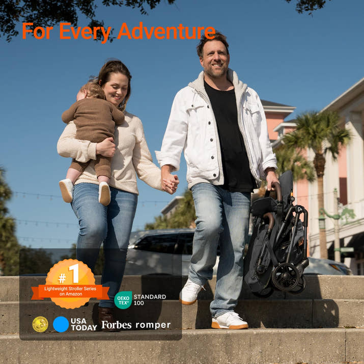 Family with a child walking outdoors, holding hands with a stroller, against a clear blue sky.